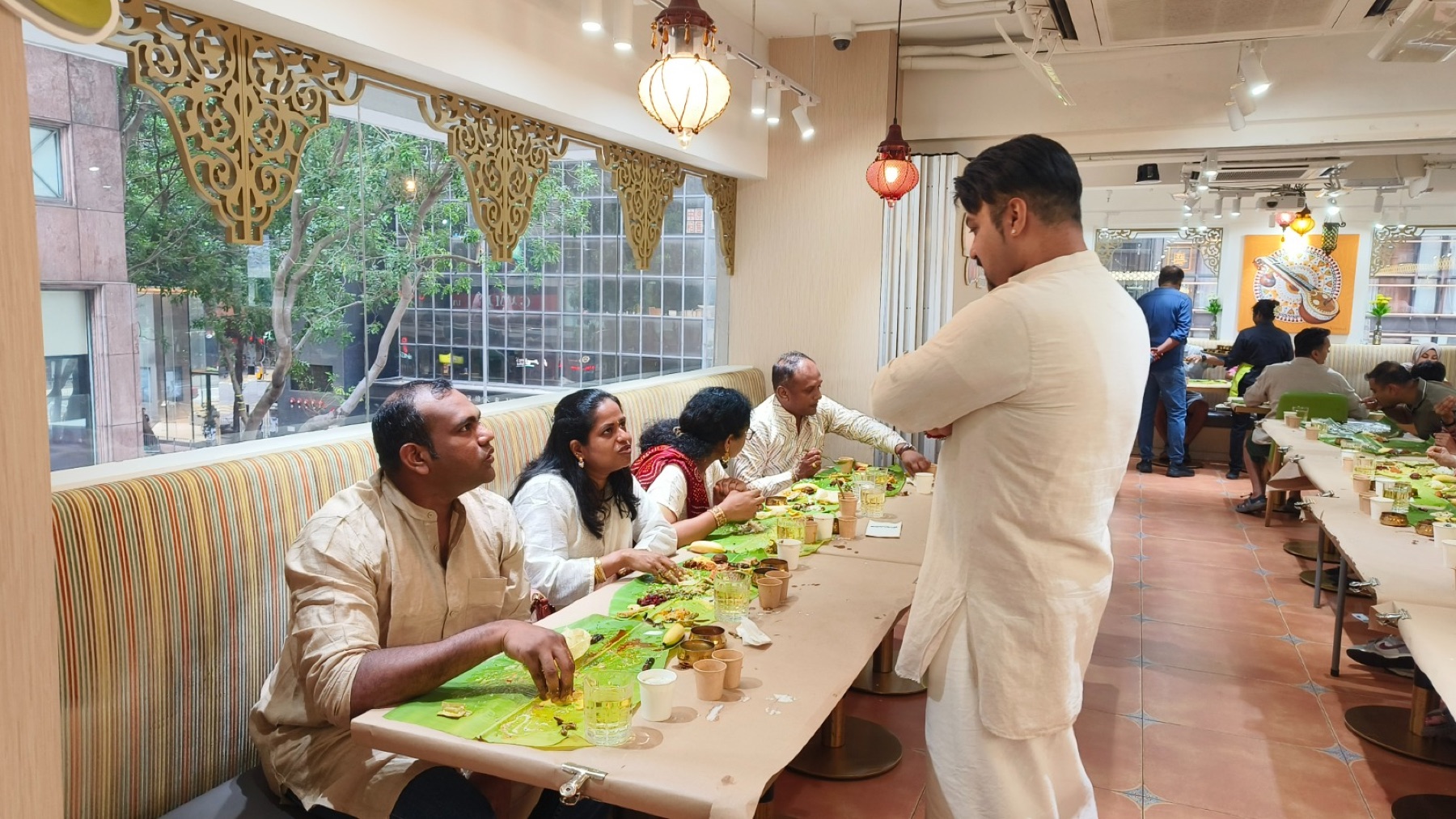 Guests seated at long tables at Woodlands Wan Chai eating Onam Sadhya served on banana leaves